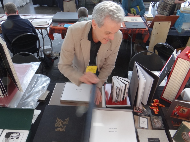 Luis Delgado displays Malulu's portfolio of John O'Leary's 'Lucha Libre' images  at the 2013 Codex in the Craneway Pavillion, Richmond, CA