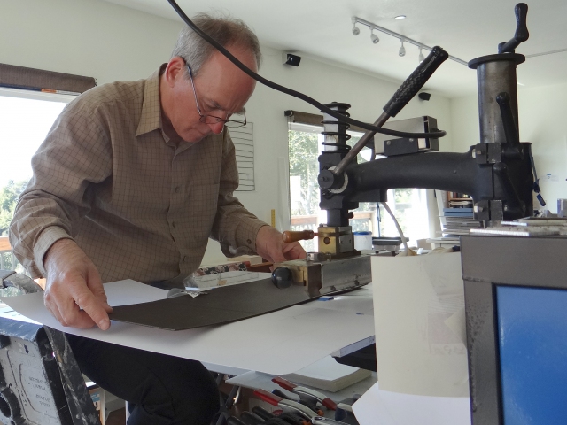 Don Drake hot foil stamping the spine titles on books in The Conversation Series, his collaboration with Kate Jordahl