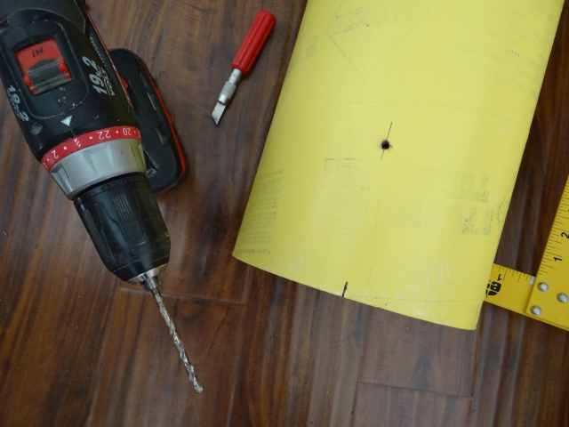 Drilling holes for rivets in the cardboard tubes during construction of a roll material storage unit.