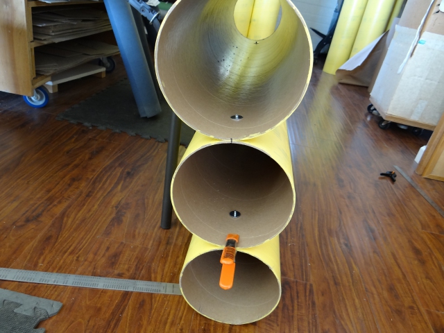 Assembling the first trio of cardboard tubes during construction of a roll material storage unit.