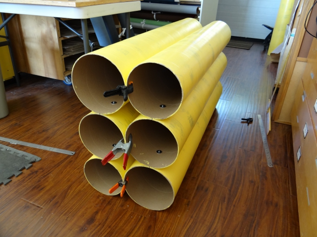 Assembling the first bank of six cardboard tubes during construction of a roll material storage unit.