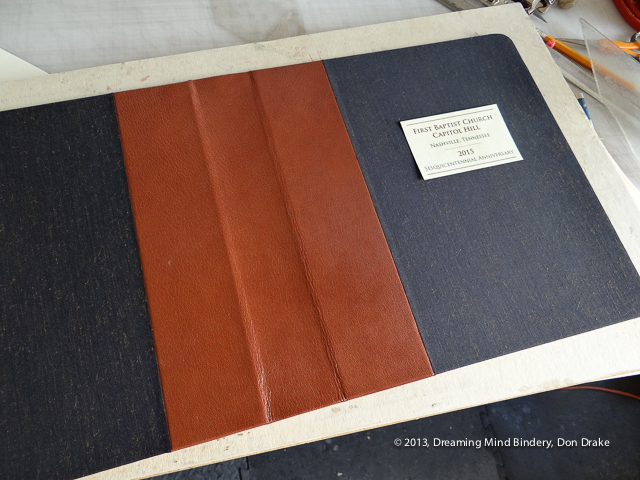 Cover of a cloth and leather notebook with a lacquered paper label laying on it while checking for size.