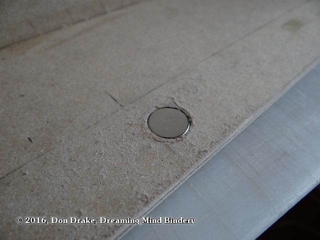 Rare earth magnet set into a hole in a box wall