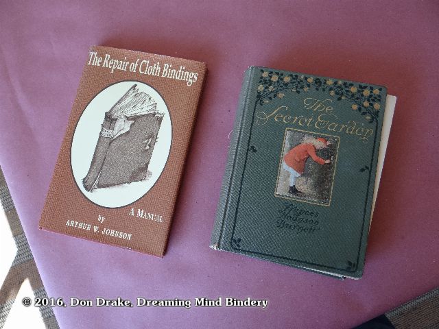 A first American edition of 'The Secret Garden' in need of repair and a copy of The Repair of Cloth Bindings (Arthur W. Johnson) on a bench top