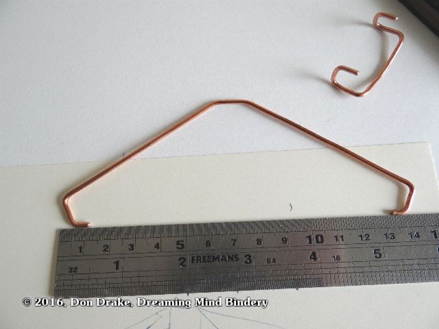 A wire bracket to hold a book open for display and photography