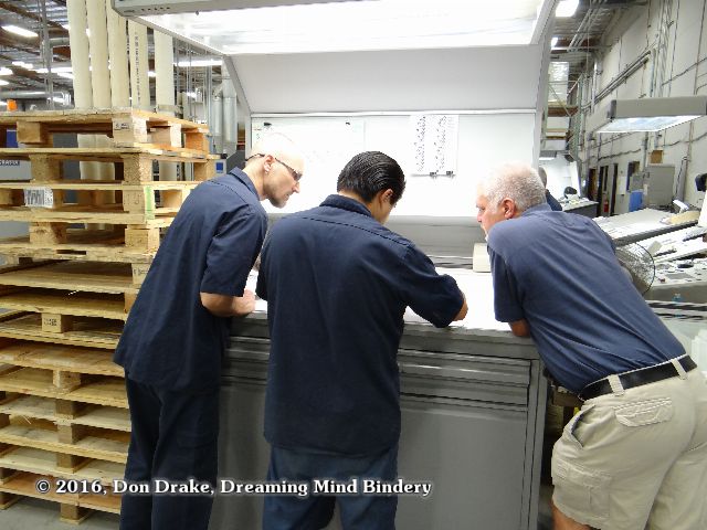 Amp Printing staff consulting over a press sheet