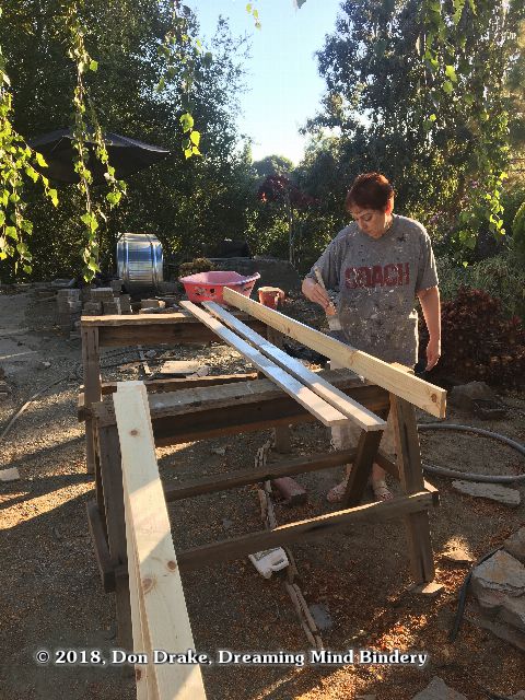 Gail primes the trim boards before putting them on the shed