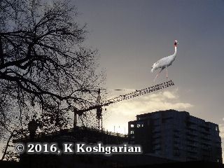 A crane photoshopped onto the boom of a construction crane silhouetted against the Portland Oregon skyline