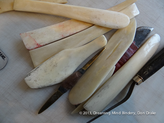 Several hand made bone folders, and a few similar tools in a random pile