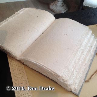 A large, hand bound blank book filled with handmade paper
